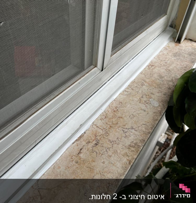 חלון עם איטום לבן על אדן השיש